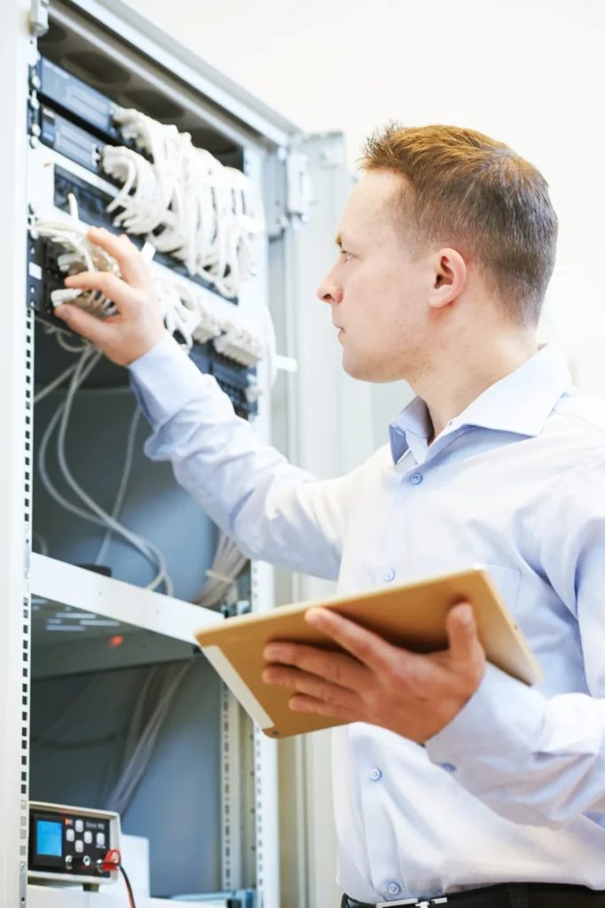 Engineer checking network switches and cabling inside a business server rack.