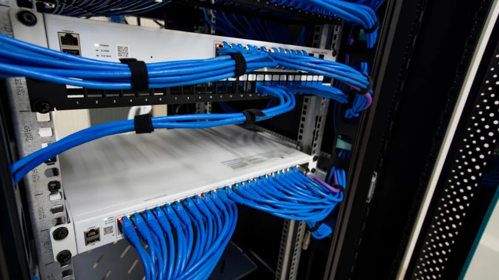 Business network switches and structured cabling inside a communications rack used for network monitoring.